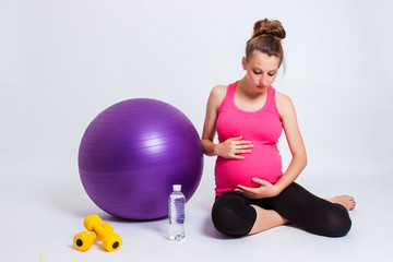 pregnant woman practicing yoga on a light background