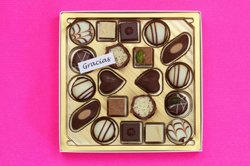 Gracias (thank you in Spanish) card with box of assorted chocolates on pink background
