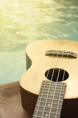 Detail of ukulele with swimming pool at the background