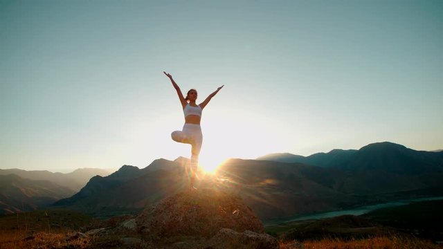4K yoga in the mountains,a beautiful girl dressed in white ,sun,sun flare, slow motion
