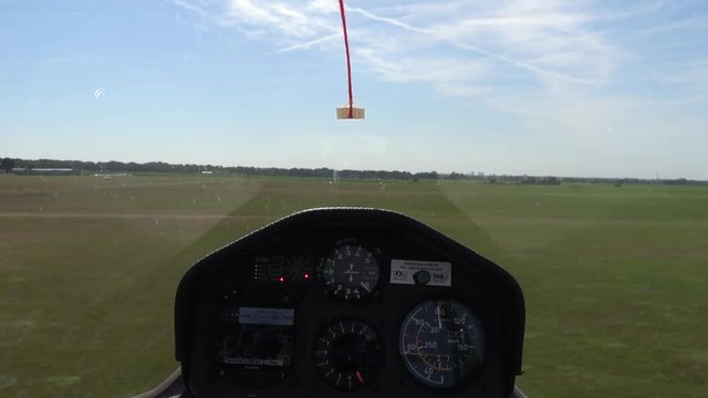 Cockpit point of view POV short footage in glider sailplane landing on grass airfield advanced instrument panel with gauges for reading altitude airspeed ascending speed beautiful day blue sky 4k
