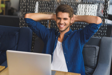 young freelancer in front of a laptop smiling with teeth