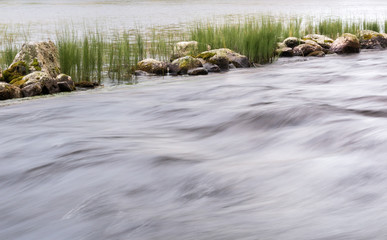 Long exposure shot of streaming water with stones in the background