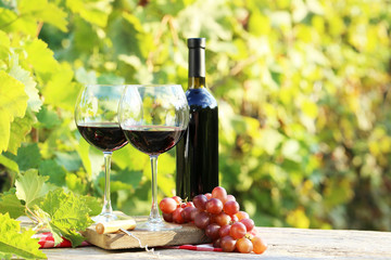 Wine in glasses with bunch of grape on wooden table