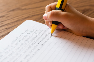 Child writing by hand on notepad