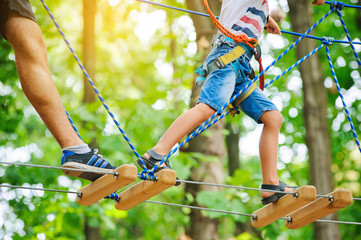 A child accompanied by an adult moves on ropes course