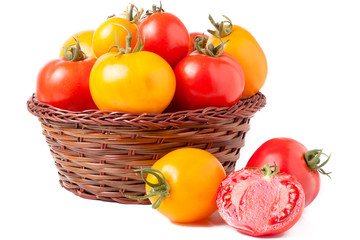 red and yellow tomatoes in a wicker basket isolated on white background