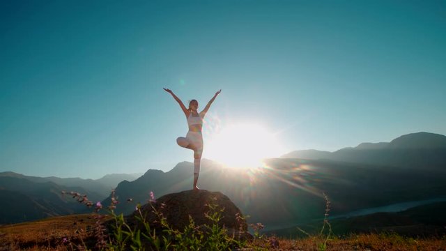 4K yoga in the mountains,a beautiful girl dressed in white ,sun,sun flare, slow motion