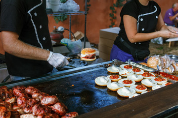 Chef preparing burgers at the barbecue outdoors