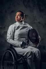 Obraz na płótnie Canvas Female fencer in wheelchair with safety mask and rapier.