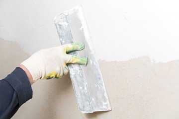 Construction worker hand plastering wall with spatula trowel tool