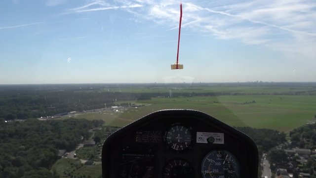 Cockpit point of view POV footage in modern glider sailplane landing on grass airfield advanced instrument panel with gauges for reading altitude airspeed ascending speed beautiful day blue sky 4k