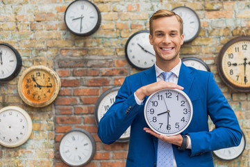 Man in suit standing near wall with clocks