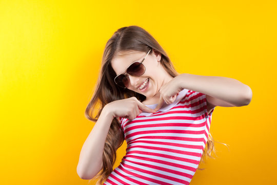 pretty girl in sunglasses posing on a yellow background. Bright stock photos. Positive human emotions