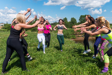 Group of excited women crossing the finshline a marathon running on grassy land in park.