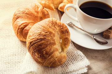 Croissant on a rustic wooden table with coffee