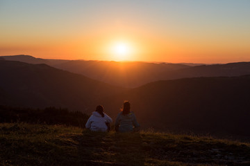 Fototapeta na wymiar 2 Personen schauen in den Sonnenuntergang, Meditation