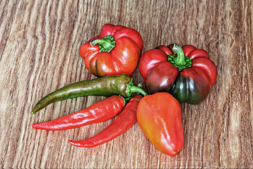 Different kinds of sweet and hot chili peppers on wooden background.