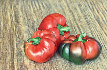 Red sweet peppers on grunge wooden background taken closeup.Toned image.