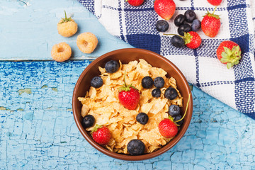 Portion of corn flakes in the bowl with different ripe berries