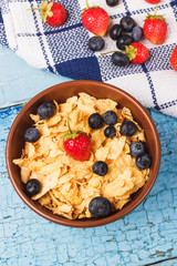Portion of corn flakes in the bowl with different ripe berries
