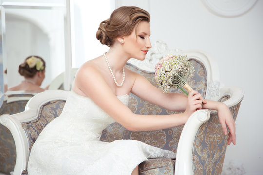 Charming bride with a bouquet in his hand in an elegant chair.
