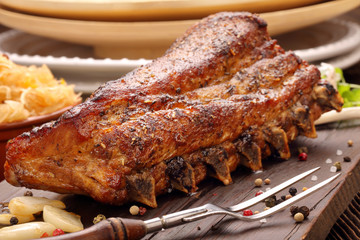 Fried pork ribs with herbs on wooden background