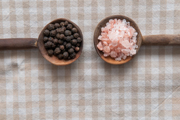 Salt and pepper seasonings of pepper corns and rock salt on wood