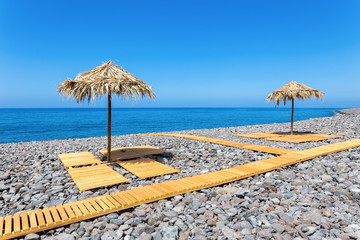 Beach umbrellas with path and stones at portuguese sea