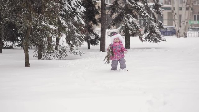 Little girl in the winter in the city is with a branch of a Christmas tree