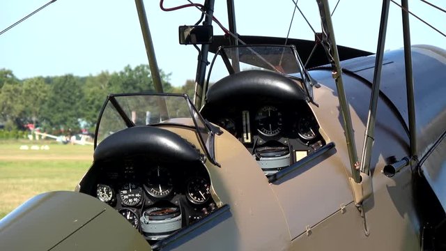 Zoom out footage of an old world war one airplane biplane fixed-wing aircraft with two main wings stacked one above the other place for two people to pilot plane very good condition grass airfield 4k