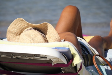 Woman sunbathing on chaise longue on the beach