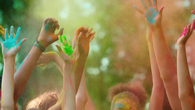 group of young friends in the Park with the colors of Holi, dancing and having fun, close-up