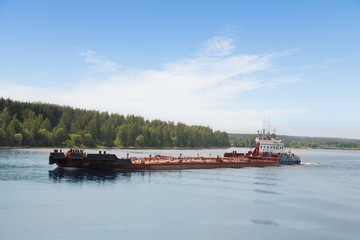 Fototapeta premium River tugboat moves barge on the Volga River