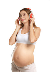 Naklejka premium Young pregnant woman with headphones isolated on white
