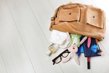 Mothers bag with accessories on wooden background