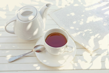 Cup of tea with shadows on wooden table