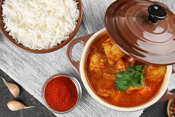 Tasty dinner with chicken curry in saucepan and rice in bowl