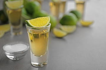 Shot of gold tequila with lime slices and salt on a tray