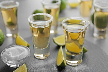 Shots of gold tequila with lime slices and salt on a tray