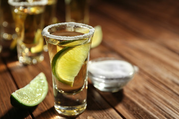 Gold tequila shot with lime on wooden background