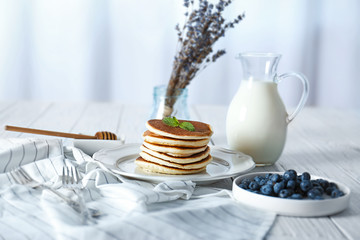 Tasty pancakes with blueberries and mint on table