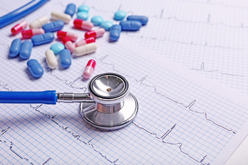 Stethoscope and pills on cardiogram, closeup