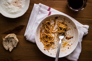 unfinished meal of spaghetti with beverage and yogurt.