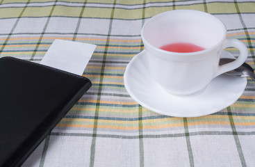 Cup of tea and a black folder with the bill for payment