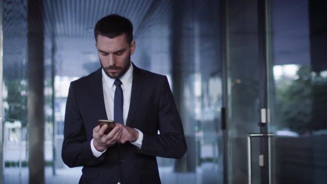 Businessman Walking on Streets of Business District and using Mobile Phone. Shot on RED Cinema Camera in 4K (UHD).