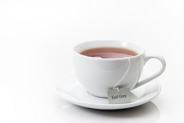 Earl Grey tea in a white cup on a saucer on a white background