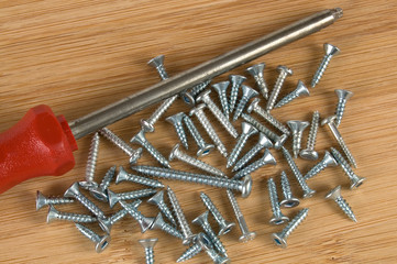 Red Screwdriver and Screws on a Wooden Table