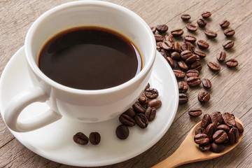 Coffee cup and coffee beans on wooden table.