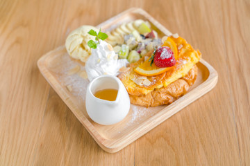 French toast with powdered sugar and a strawberry on wood table